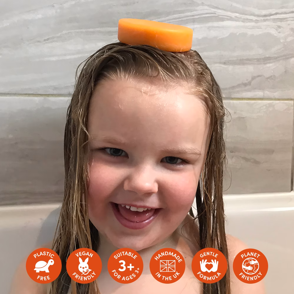 Child with soap bar on head, smiling.