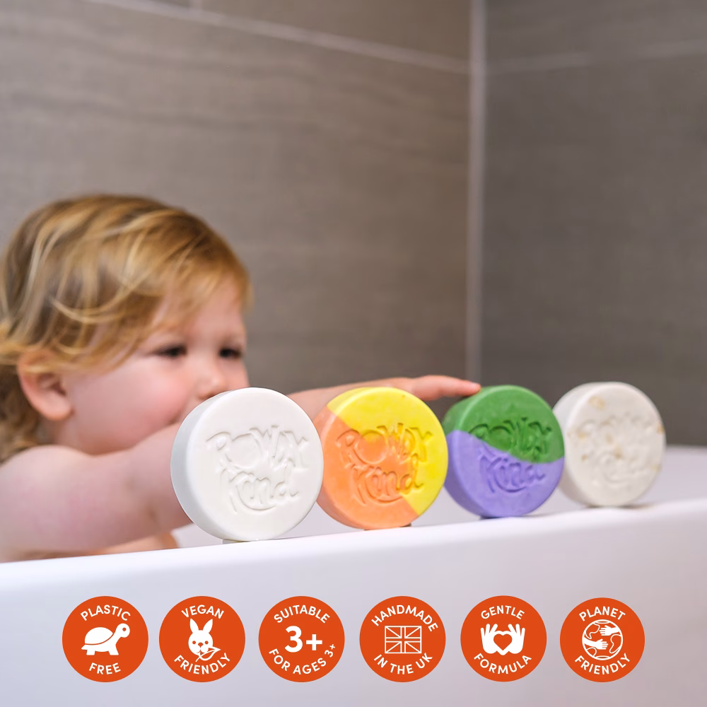 Child with colorful soap bars in bathtub.