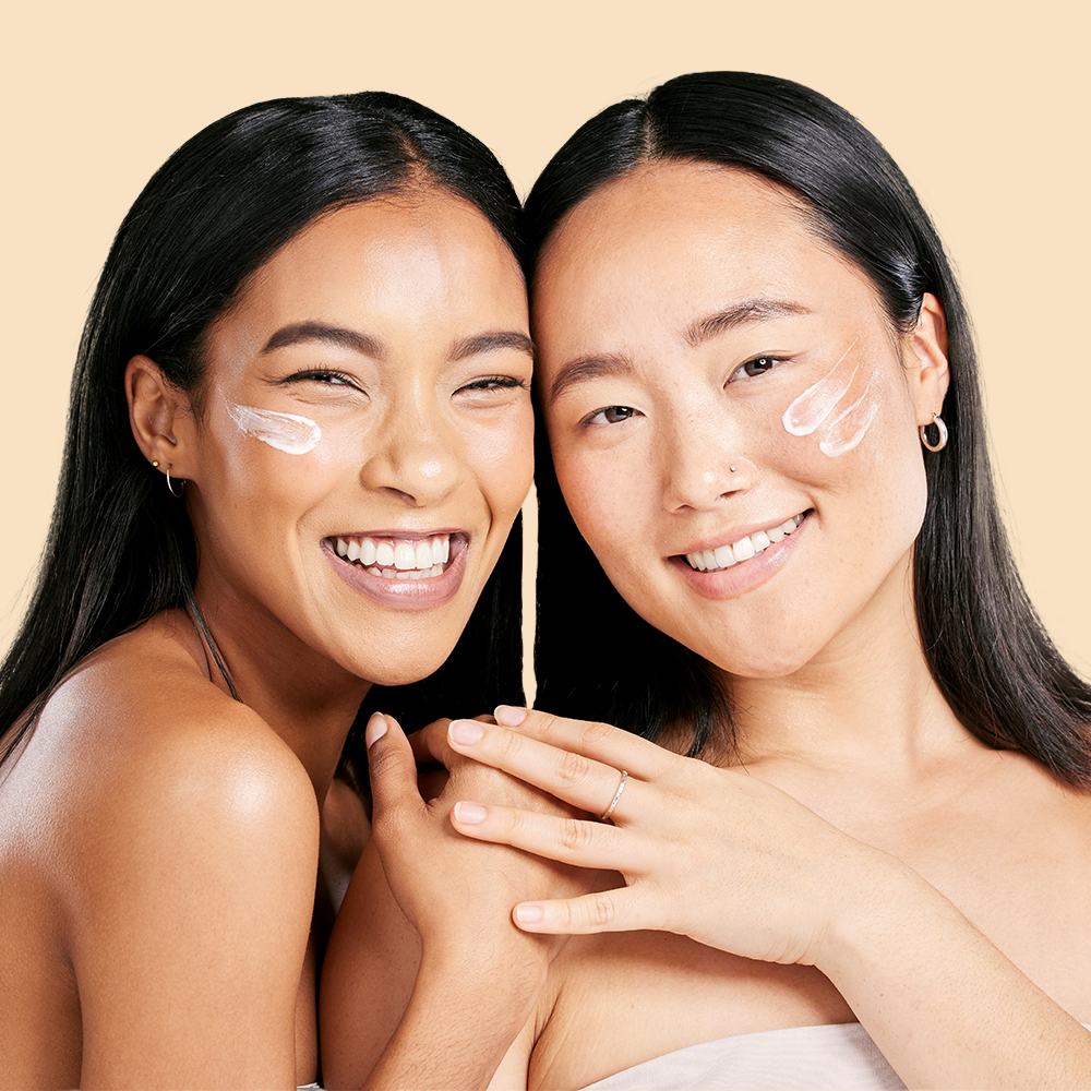 Two women smiling with cream on cheeks.