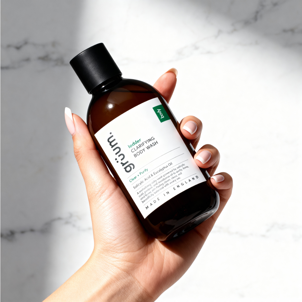 Hand holding clarifying body wash bottle.