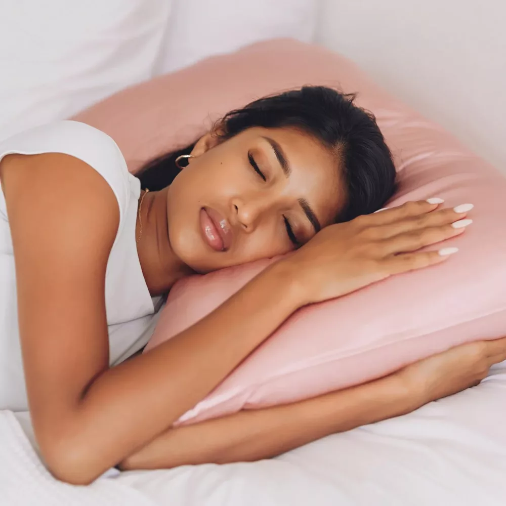 Woman laying on satin pink pillow case